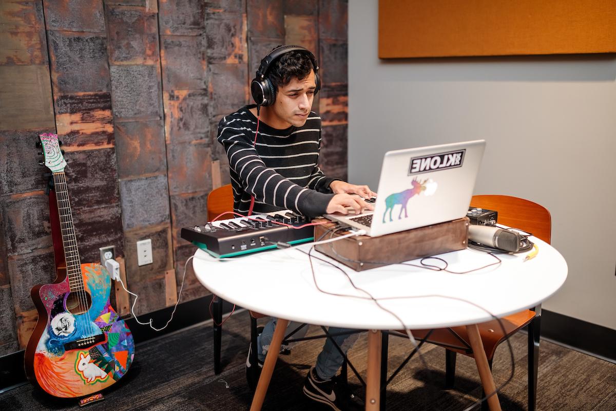 密歇根州立大学丹佛分校的一名学生坐在桌子旁创作音乐