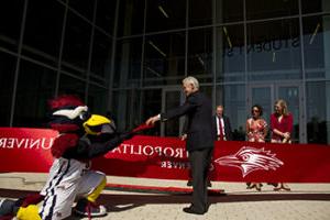 Rowdy Roadrunner mascot handing scissors to president Jordan in front of the newly-opened Student Success Building
