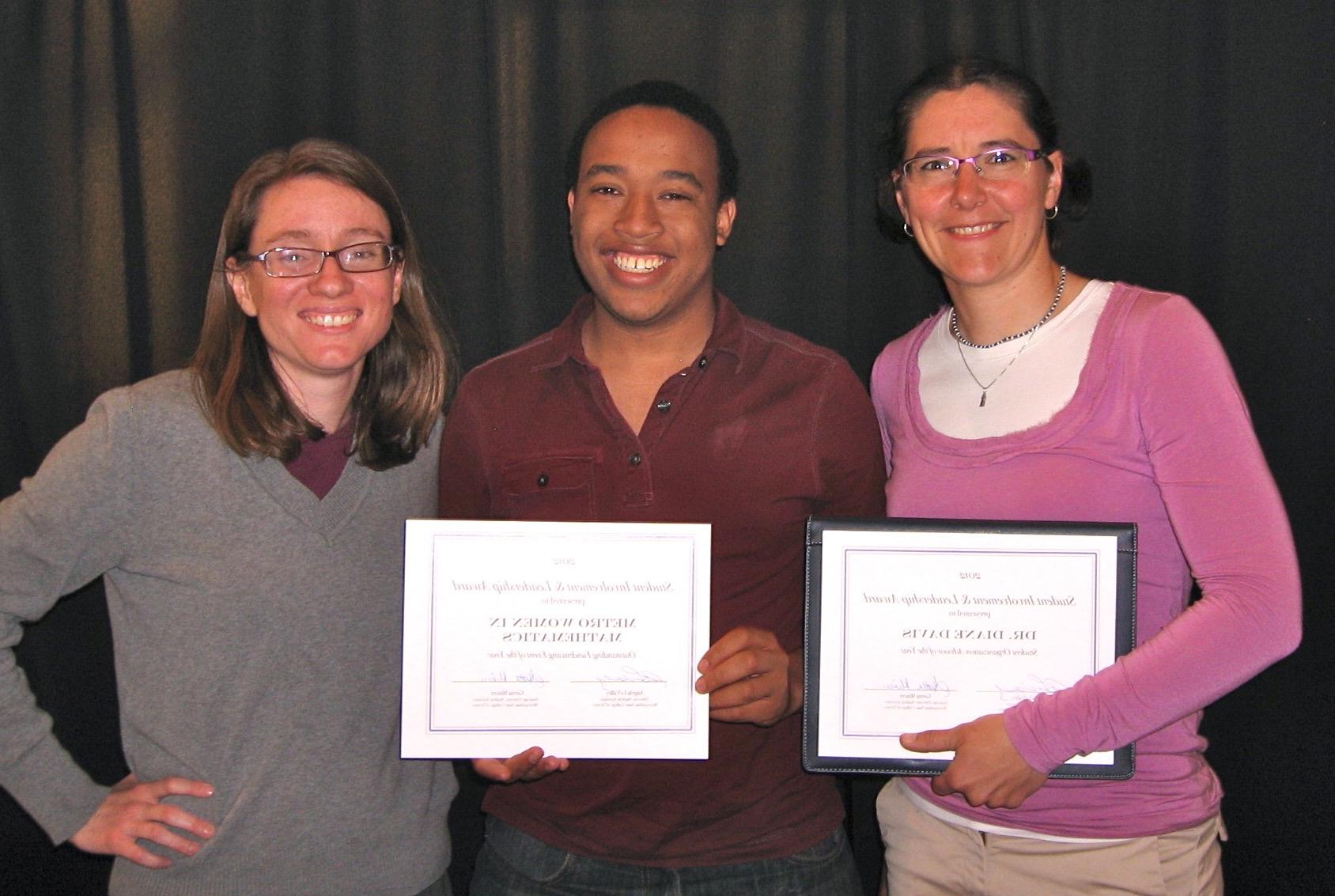 Three people standing and holding certificates