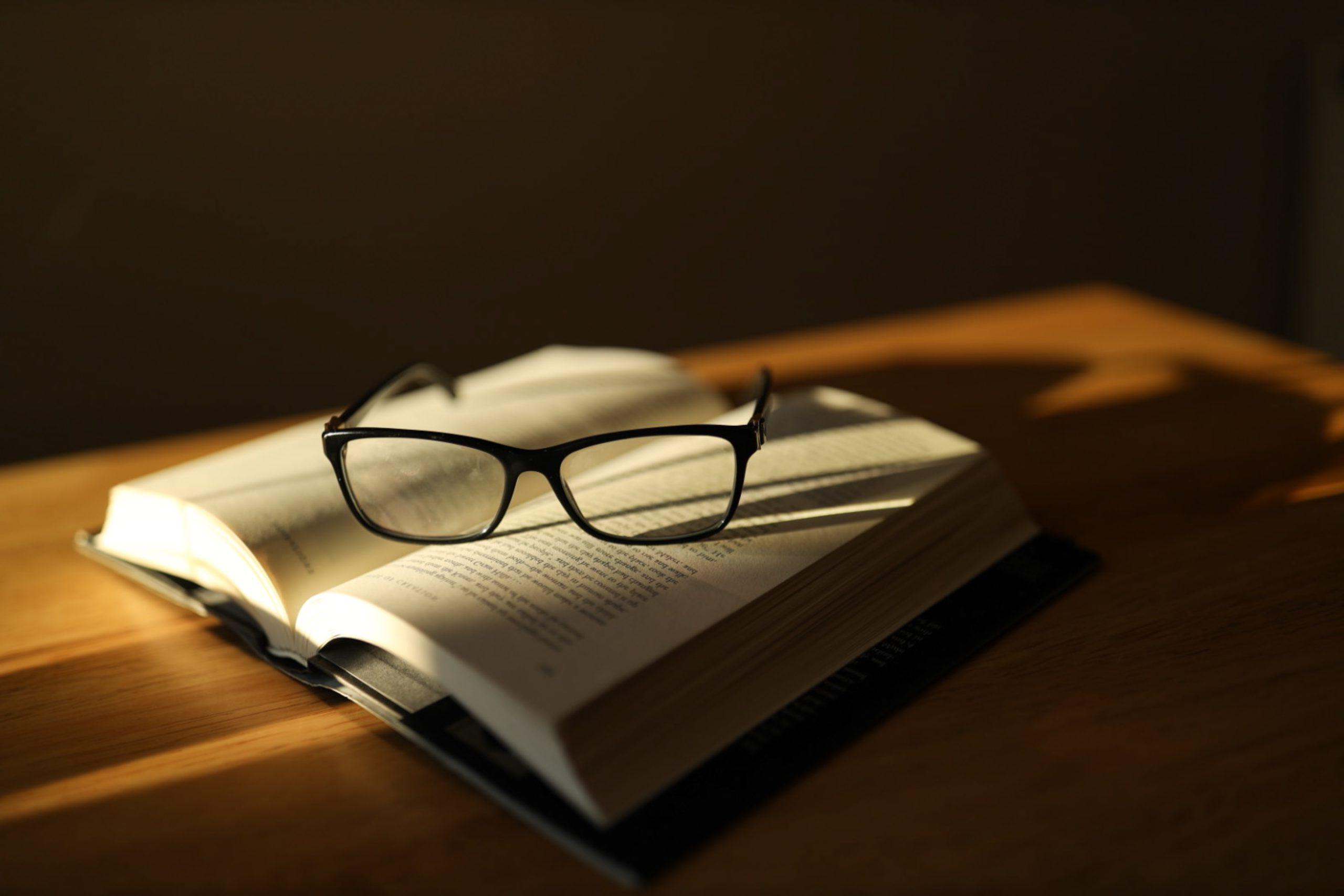 An open book with a pair of black glasses