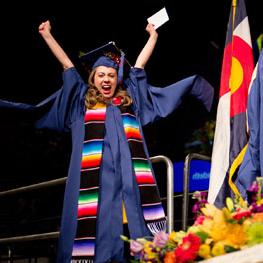 A graduate cheering as they cross the stage at commencement